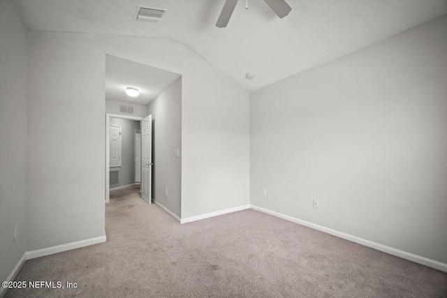carpeted spare room featuring visible vents, a ceiling fan, baseboards, and vaulted ceiling