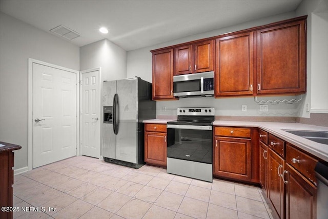 kitchen featuring light countertops, stainless steel appliances, visible vents, and light tile patterned floors