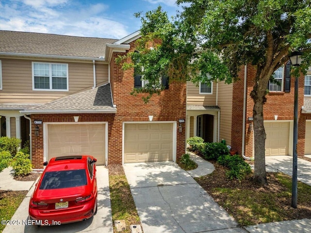 townhome / multi-family property featuring brick siding, driveway, roof with shingles, and a garage