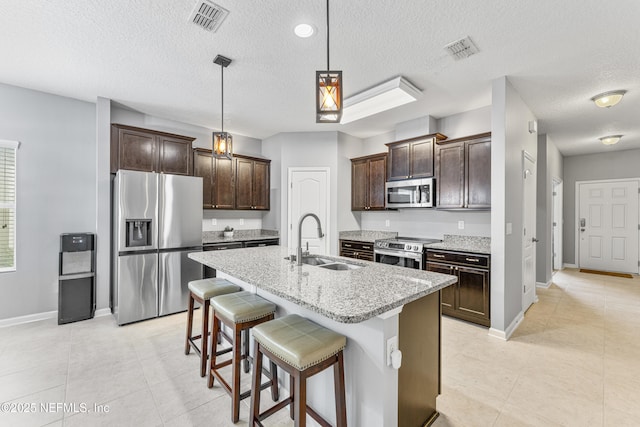kitchen with dark brown cabinetry, appliances with stainless steel finishes, a sink, and visible vents