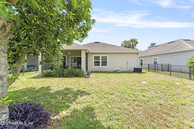 rear view of house featuring a yard, a fenced backyard, and stucco siding