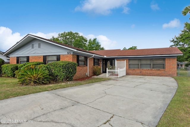 ranch-style home featuring fence, concrete driveway, a front lawn, and brick siding