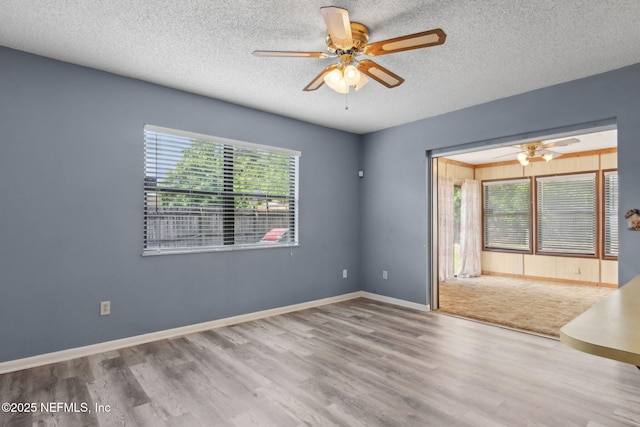 empty room featuring baseboards, a textured ceiling, ceiling fan, and wood finished floors