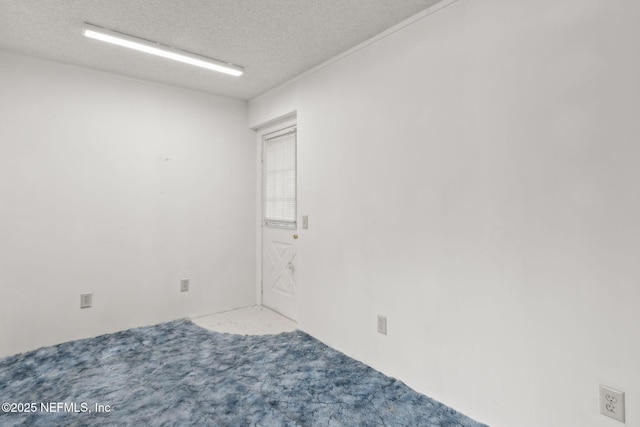 carpeted empty room featuring a textured ceiling