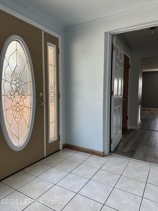 foyer featuring baseboards, ornamental molding, and light tile patterned floors