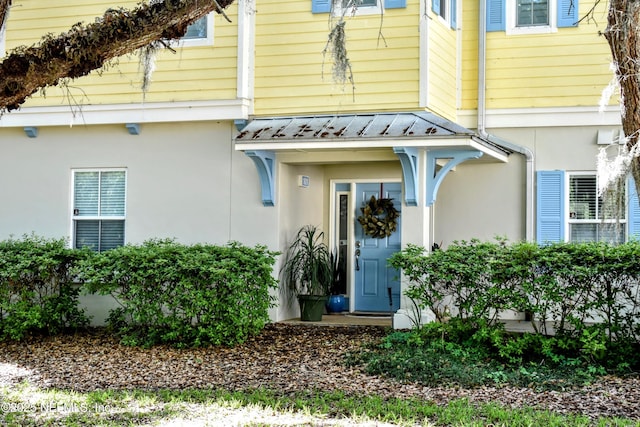 doorway to property with a standing seam roof, metal roof, and stucco siding