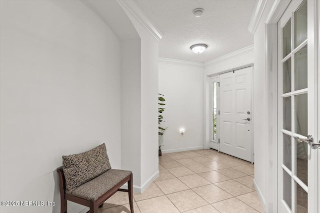 foyer with crown molding, baseboards, a textured ceiling, and light tile patterned floors