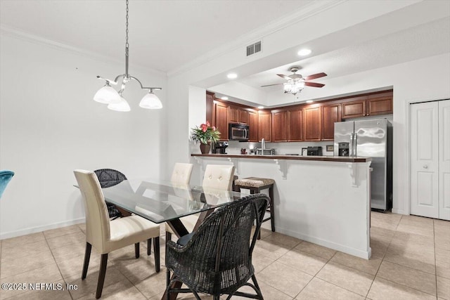 dining area with crown molding, light tile patterned flooring, ceiling fan with notable chandelier, baseboards, and visible vents