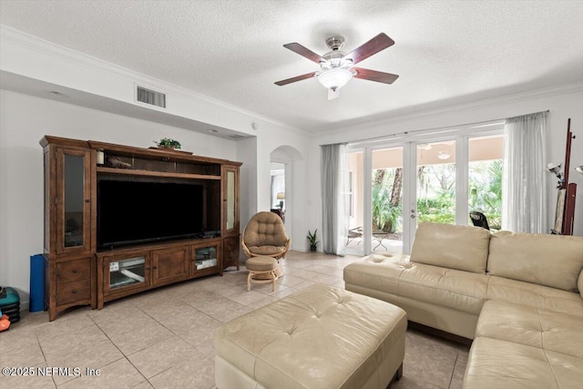 living room with visible vents, a ceiling fan, crown molding, and arched walkways