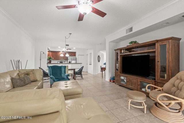 living area featuring crown molding, ceiling fan, light tile patterned flooring, and visible vents