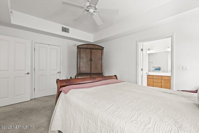 carpeted bedroom with ceiling fan, visible vents, and ensuite bathroom