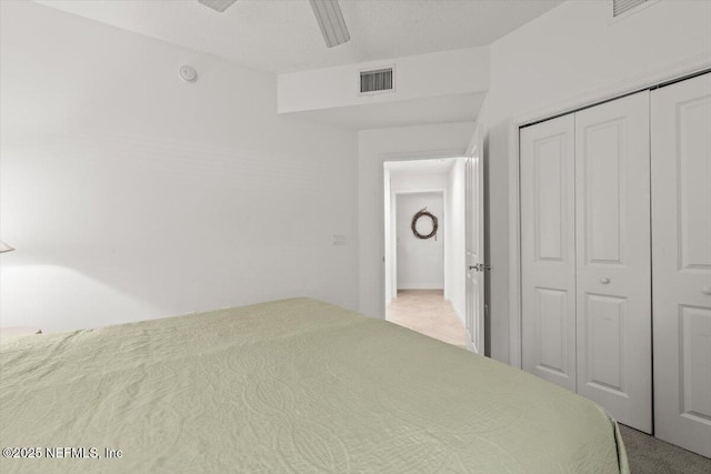carpeted bedroom with ceiling fan, visible vents, and a closet