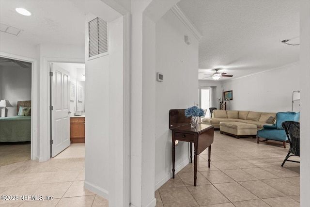 living area with ceiling fan, a textured ceiling, visible vents, crown molding, and light tile patterned floors