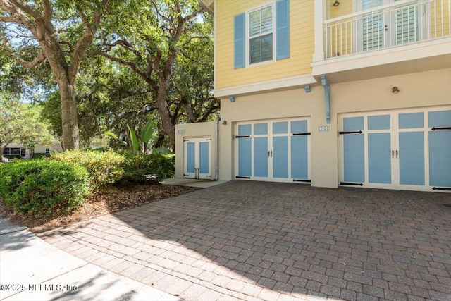 exterior space featuring an attached garage, stucco siding, and decorative driveway