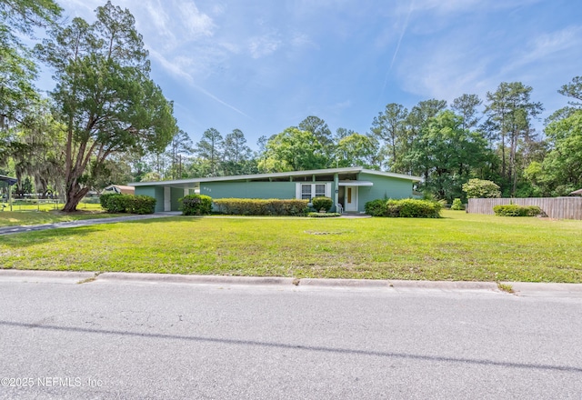 mid-century modern home with fence, driveway, a front yard, and an attached carport