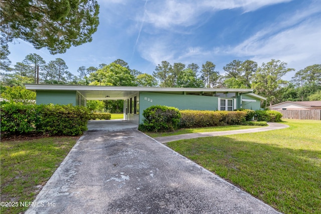 view of front of property with a front lawn, aphalt driveway, fence, and an attached carport