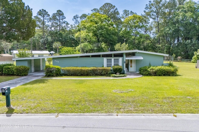 mid-century inspired home with concrete driveway, an attached carport, and a front yard