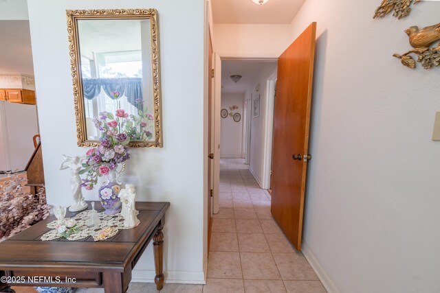 corridor featuring light tile patterned floors and baseboards