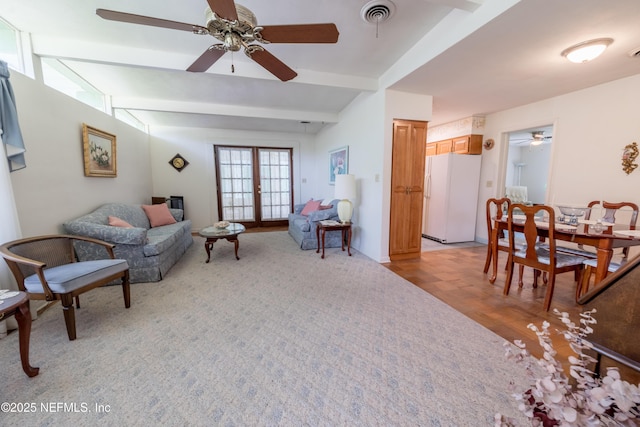 living room with beamed ceiling, a ceiling fan, light wood finished floors, and visible vents