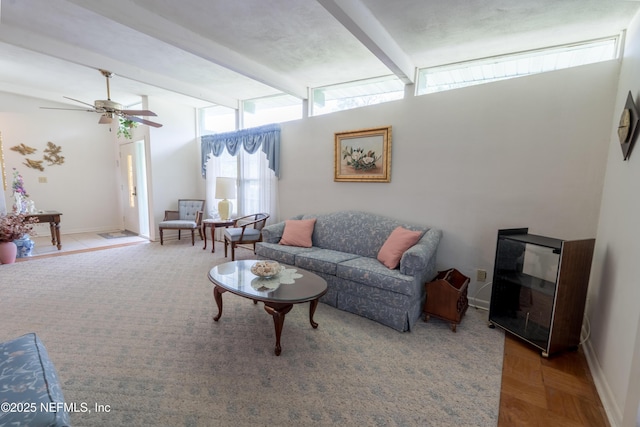 living area featuring a ceiling fan, beamed ceiling, and baseboards