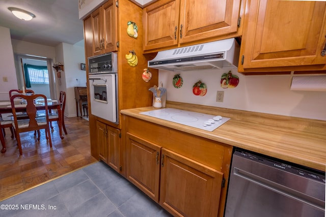 kitchen featuring light countertops, ventilation hood, brown cabinets, and white appliances
