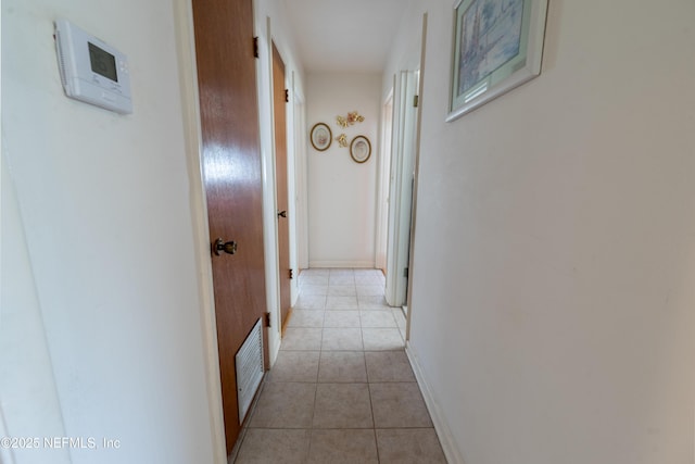 hall with baseboards, light tile patterned flooring, and visible vents