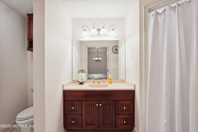 full bath featuring an inviting chandelier, vanity, toilet, a textured ceiling, and baseboards