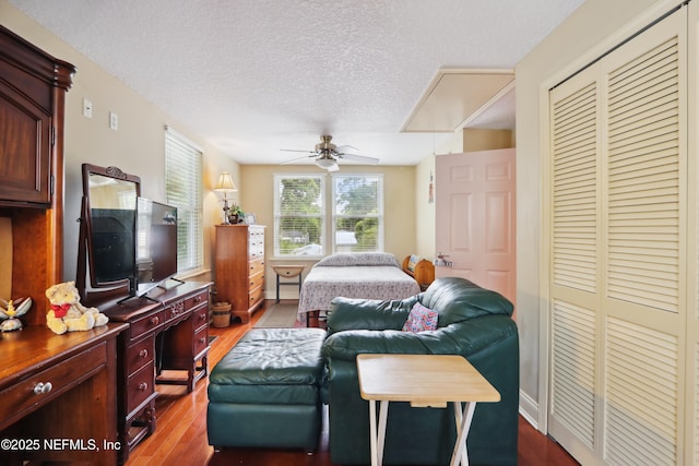 bedroom featuring dark wood-type flooring, a ceiling fan, a textured ceiling, and a closet