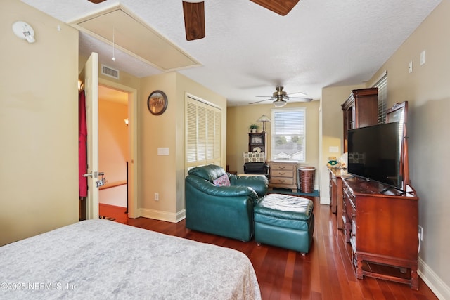 bedroom featuring visible vents, dark wood-style flooring, baseboards, attic access, and a ceiling fan