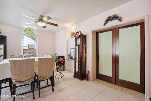 dining space with light tile patterned flooring, ceiling fan, and a textured ceiling