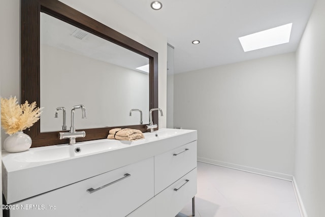 full bath with a skylight, double vanity, baseboards, and recessed lighting