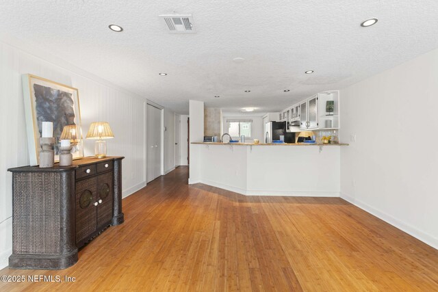 living area featuring wood finished floors, a textured ceiling, baseboards, and recessed lighting