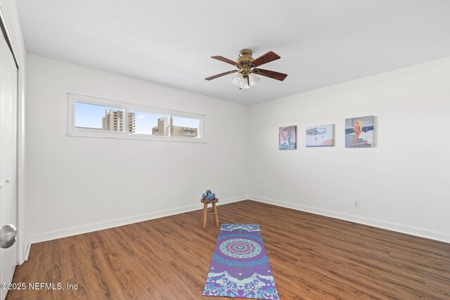 unfurnished room featuring wood finished floors, a ceiling fan, and baseboards