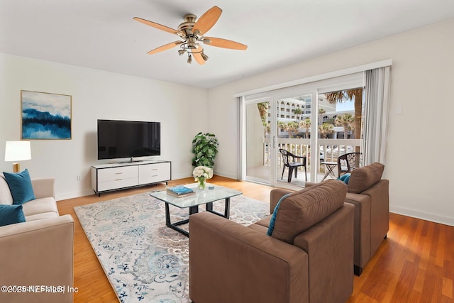 living area with ceiling fan, baseboards, and light wood-type flooring