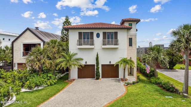 mediterranean / spanish-style house featuring an attached garage, a front lawn, stucco siding, decorative driveway, and a balcony
