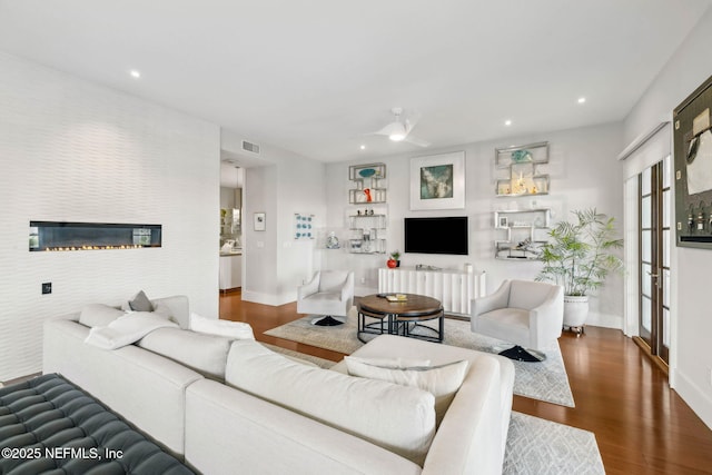living room with recessed lighting, baseboards, visible vents, and wood finished floors