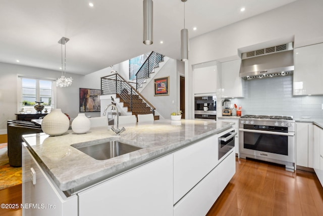 kitchen with a sink, modern cabinets, stainless steel range, and range hood