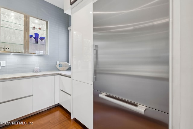 kitchen featuring light stone countertops, dark wood-type flooring, white cabinetry, tasteful backsplash, and stainless steel built in refrigerator