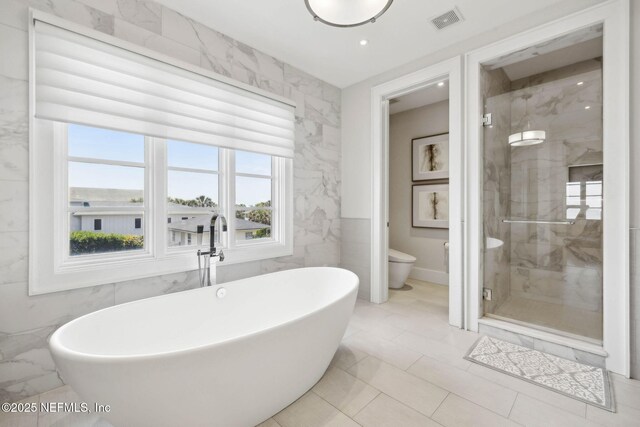 full bathroom with visible vents, a freestanding tub, toilet, tile walls, and a shower stall