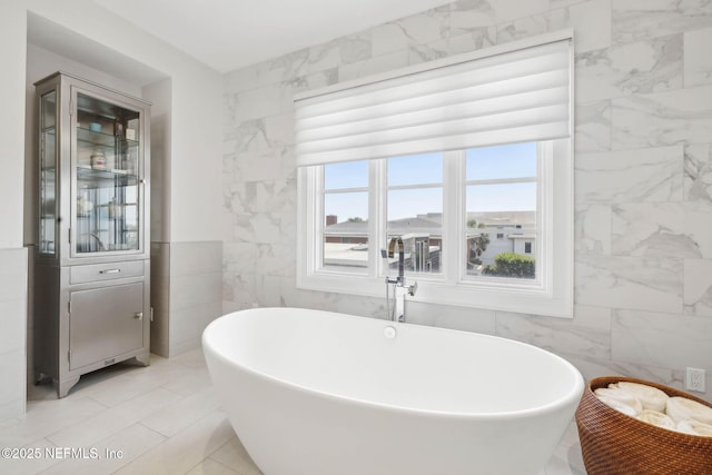 bathroom featuring a freestanding tub and tile walls