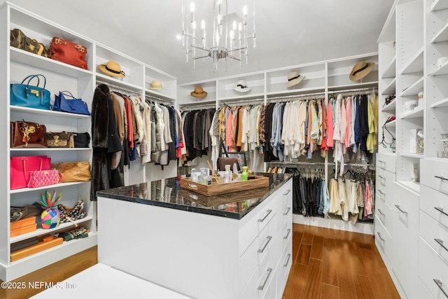 spacious closet with a notable chandelier and wood finished floors