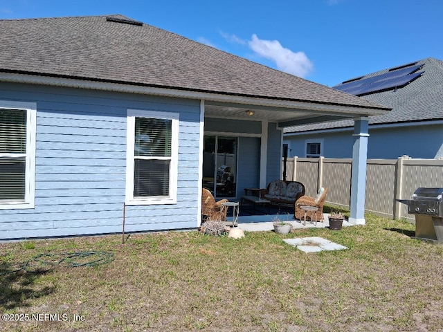 rear view of house featuring fence, a yard, a patio area, and roof with shingles