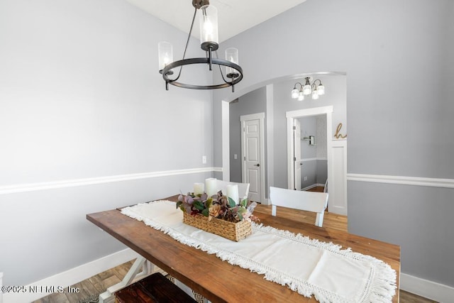 45103 Amhurst Oaks Dr, Callahan, FL 32011 - dining room featuring a chandelier, arched walkways, wood finished floors, and baseboards