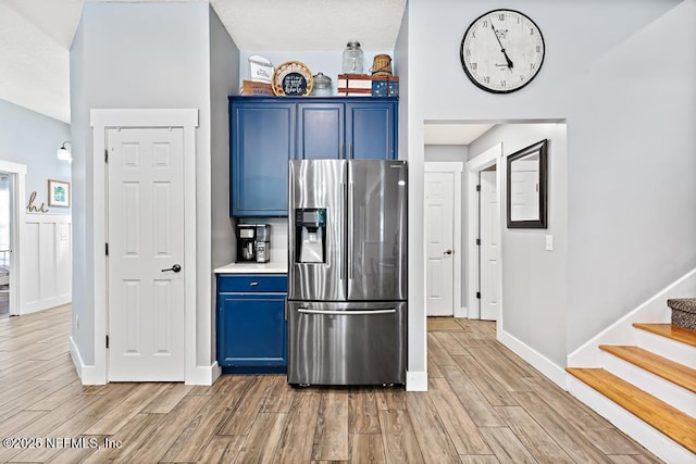 45103 Amhurst Oaks Dr, Callahan, FL 32011 - kitchen with stainless steel fridge, blue cabinets, baseboards, and light wood finished floors