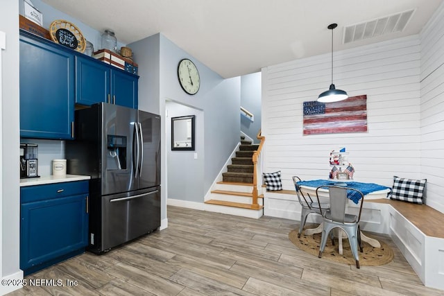 45103 Amhurst Oaks Dr, Callahan, FL 32011 - kitchen with stainless steel fridge, blue cabinets, light wood-style floors, and hanging light fixtures