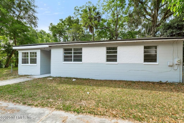 ranch-style home with concrete block siding and a front yard