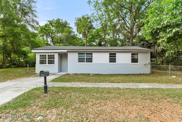 ranch-style house featuring fence and a front yard