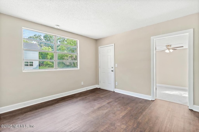 empty room with dark wood-type flooring, a textured ceiling, and baseboards