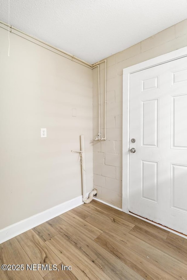 clothes washing area featuring baseboards and light wood finished floors