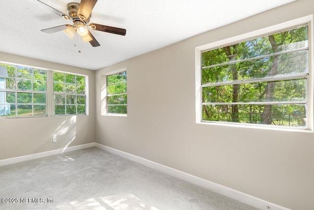 carpeted empty room with baseboards and a ceiling fan